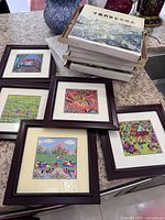 All five framed embroideries with stack of storage boxes