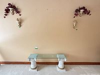 Overall view of wall decor, table, pedestals, cherub shelves, foliage and figurine