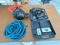 Overview of saw, drill set in case, blue hose
