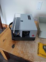 Projector with slide magazine tray inserted and plastic slide storage box