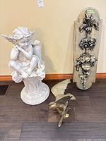 Group shot of cherub statue, wall plaque and brass eagle parts