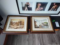 Both framed paintings side by side on table