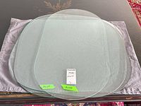 All three glass table tops stacked: one larger square-round and two rectangular-round