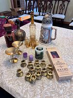 Group shot of all items including decanter set, stein, brass pieces, bottles and candles