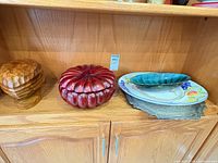 Shelf view of all five items: wooden nut bowl, red pumpkin dish, Blue Mountain leaf dish, fruit platter, metal tray