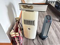 Amcor air conditioner with exhaust hose and window adapter alongside Sunbeam heater