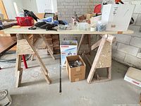 Pair of wooden sawhorses beneath door panel; other objects present for scale