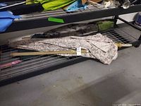 Folded floral patio umbrella with pole pieces on wire rack