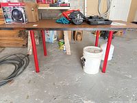 Full view of table showing red legs and brown veneer top
