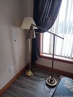 Both floor lamps standing together beside window