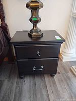 Front view of nightstand showing top surface, drawer arrangement, hardware, and finish
