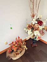 Tall floor vase with silk flower arrangement and branches beside low planter