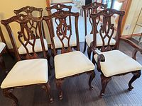 Front view of four chairs showing carved backs and seats