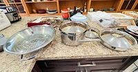 Full set on countertop: frying pan, stockpot, steamer insert, lids
