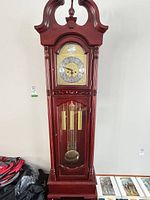 Full view of wooden grandfather clock showing case, door, weights, pendulum