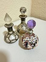 Front view of three perfume bottles showing designs and stoppers