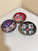 Top view of three hand-painted bowls showing colors and patterns