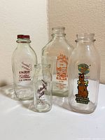 Group of four glass milk bottles showing labels and relative sizes