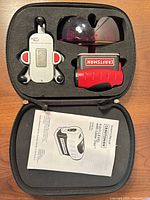 Case open showing laser level, wall mount, safety glasses, manual.