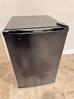 Front view of black Frigidaire mini fridge showing exterior and scratches