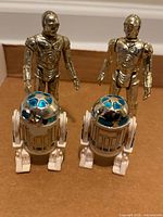 Front view of two C-3PO and two R2-D2 figures upright on surface
