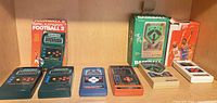 Six Mattel handheld games arranged on shelf with two original boxes