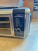 Control panel close-up showing function list and knob, basket partially visible