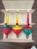Three bubble light bulbs on cardboard insert showing colours and bases