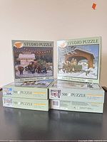 Stack of six Studio Puzzle 500-piece boxes, two fronts visible
