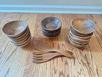 Three stacks of walnut bowls and two servers laid out on hardwood floor