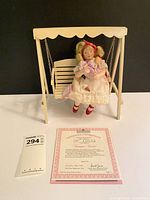 Doll on swing with certificate in foreground
