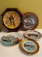Group shot of all five plates—two framed, three loose—showing size and themes