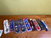 Eight carded/cased souvenir spoons laid out side by side