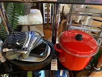 Group on shelf showing towels, mitts, roasting pans, bake pans and red stock pot