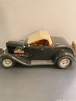 Full side view of black 1932 Ford roadster model car with tan hardtop and exposed engine