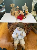 Group shot of all plush toys on white backdrop and porcelain doll seated in wicker chair