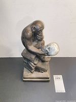 Full front view of ape sculpture on books holding skull