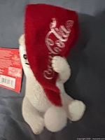 Front view of polar bear ornament holding red Coca-Cola hat