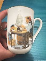 Front scene of mug with Norman Rockwell artwork and maker mark visible