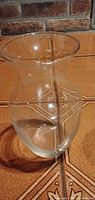 Clear flared-rim glass vase on tile surface