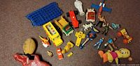 Group of toys laid out showing vehicles, figures, plush items and grid panels