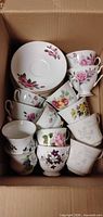 Box containing assorted floral teacups and saucers