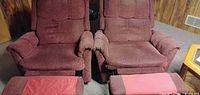 Front view of both burgundy rocker recliners showing attached footrests