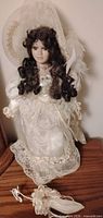 Full view of porcelain doll on stand with lace parasol