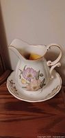Pitcher on basin showing floral design and gold trim