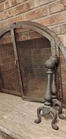 Arched wrought iron screen front view with one andiron