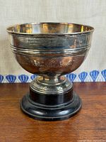 Front view of silver-plated trophy on base showing overall form