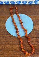 Full view of amber chip necklace coiled on wood surface