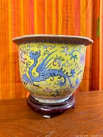 Front view of yellow Famille Rose planter on wooden stand