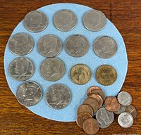 Overall view: 14 Kennedy half-dollars on blue felt, 2 golden dollars, 8 Lincoln cents